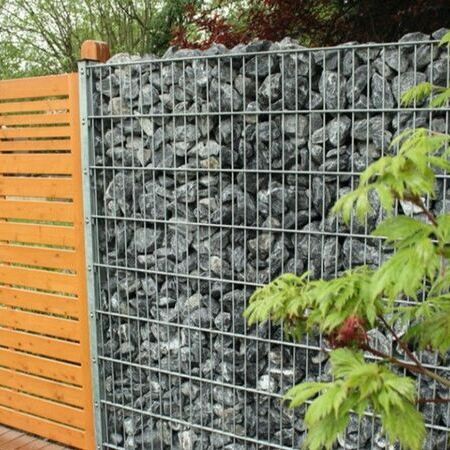 Gabione Eckpfostensystem in Verlängerung eines Holzsichtschutzes.