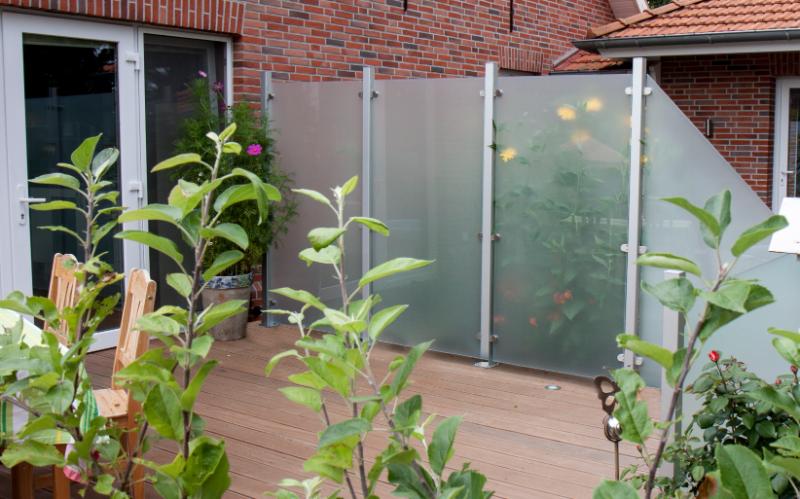 Groja Ambiente - Sichtschutz aus satiniertem Glas auf Holzterrasse vor Backsteinwand mit Pflanzen im Vordergrund