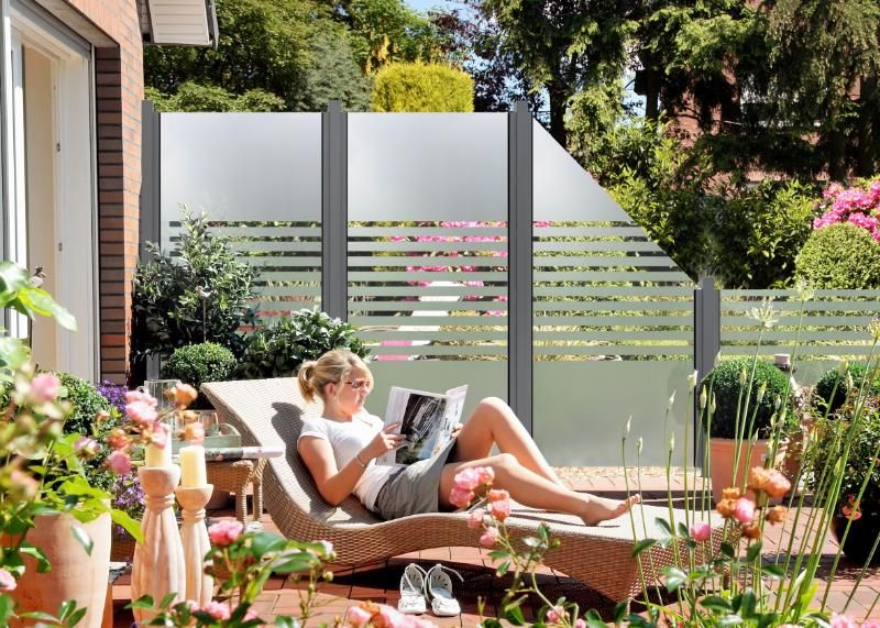 Groja Ambiente streifen - Frau liegt auf einer Liege im Garten vor einer Sichtschutzwand mit horizontalen Streifen und liest eine Zeitschrift