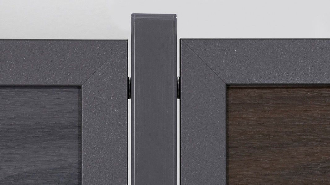 Groja Viento - Nahaufnahme eines grauen Metallpfostens zwischen zwei dunkelgrauen Türrahmen mit Holzfüllung