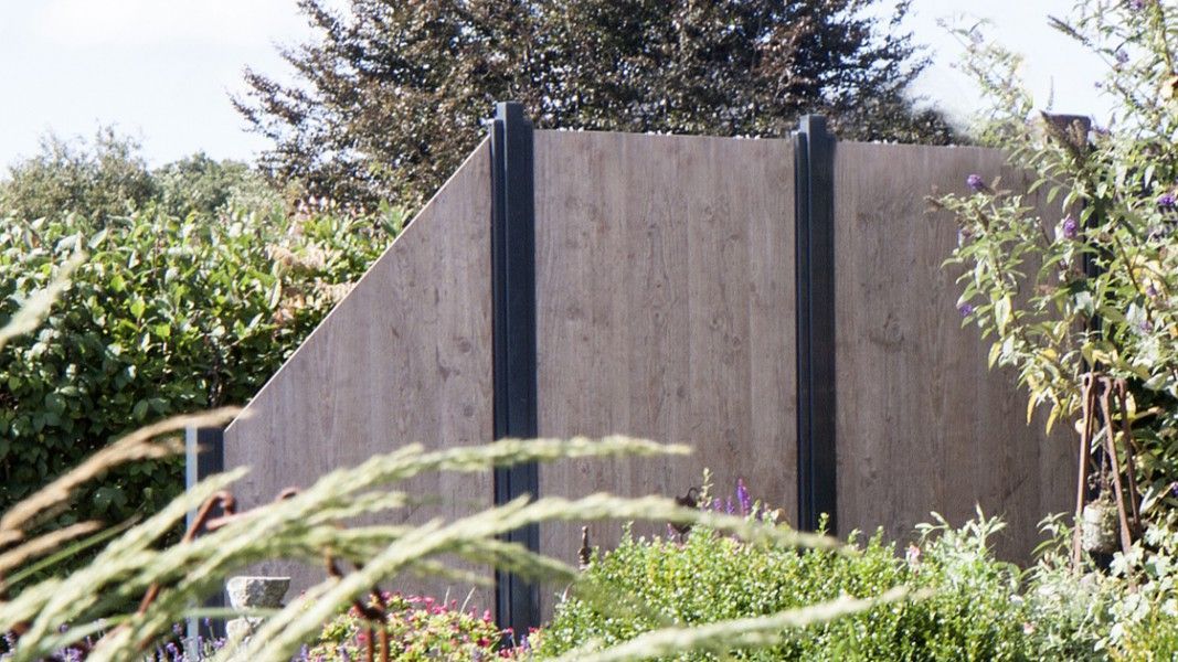 Groja Premo - Holzsichtschutzwand mit schwarzer Metallunterstützung im Garten vor Büschen und Bäumen