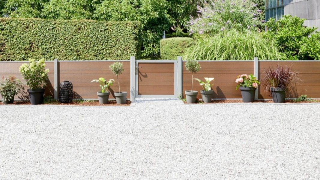 Traumgarten System WPC Platinum Sichtschutzzaun braun mit Eingangstor im Kiesgarten
