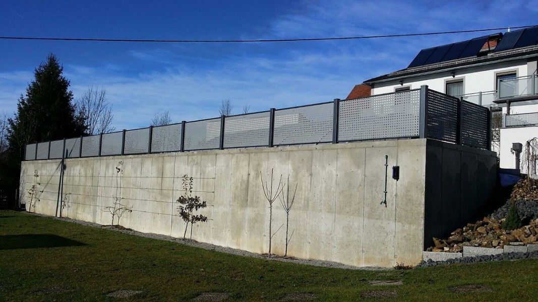 Guardi Loos Lochblechzaun silber auf Betonmauer, moderner Sichtschutzzaun Straße