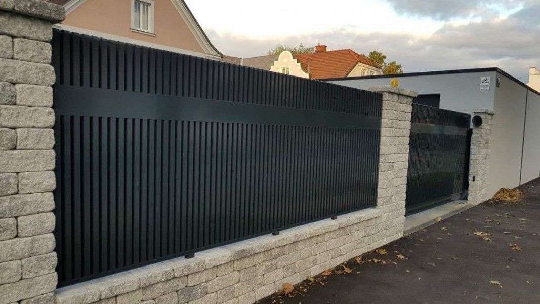Guardi Epos Aluzaun anthrazit auf Steinmauer, exklusiver Designzaun Einfahrt